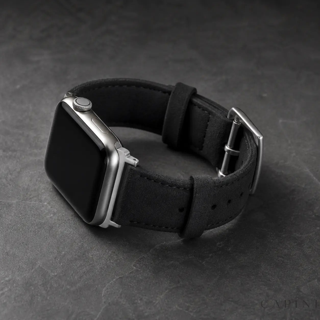 Black Monza Alcantara Apple Watch strap with silver hardware on dark stone