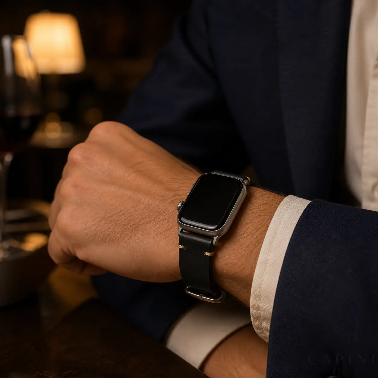 Black Trieste oil-wax Apple Watch strap with silver hardware worn with a navy blazer