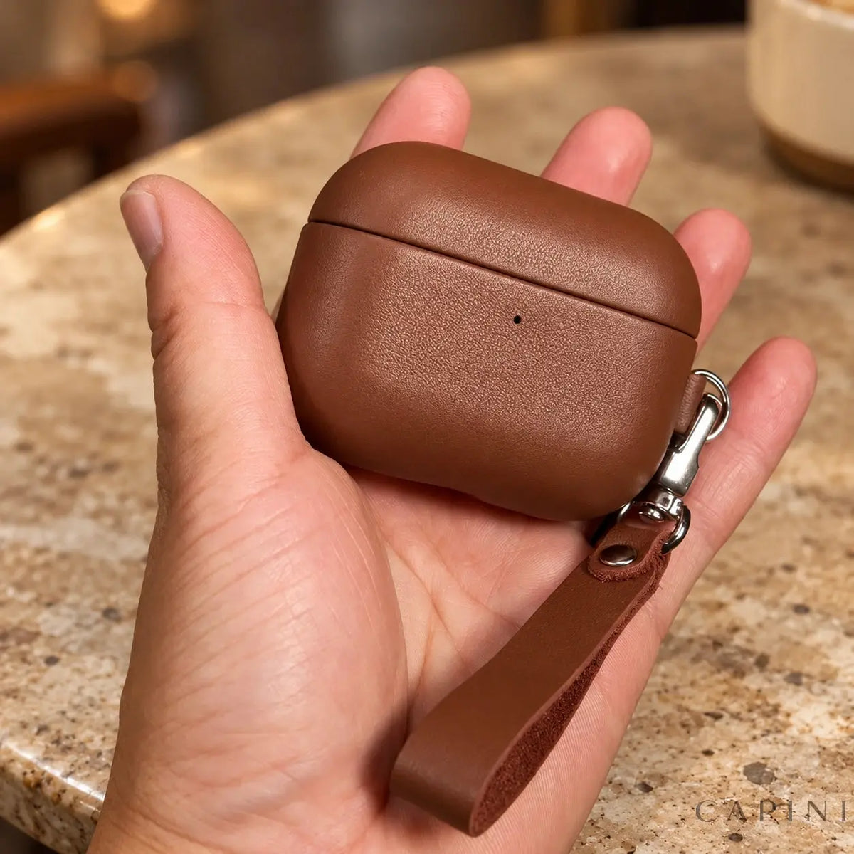 Biella leather AirPods case held in hand with detachable wrist strap