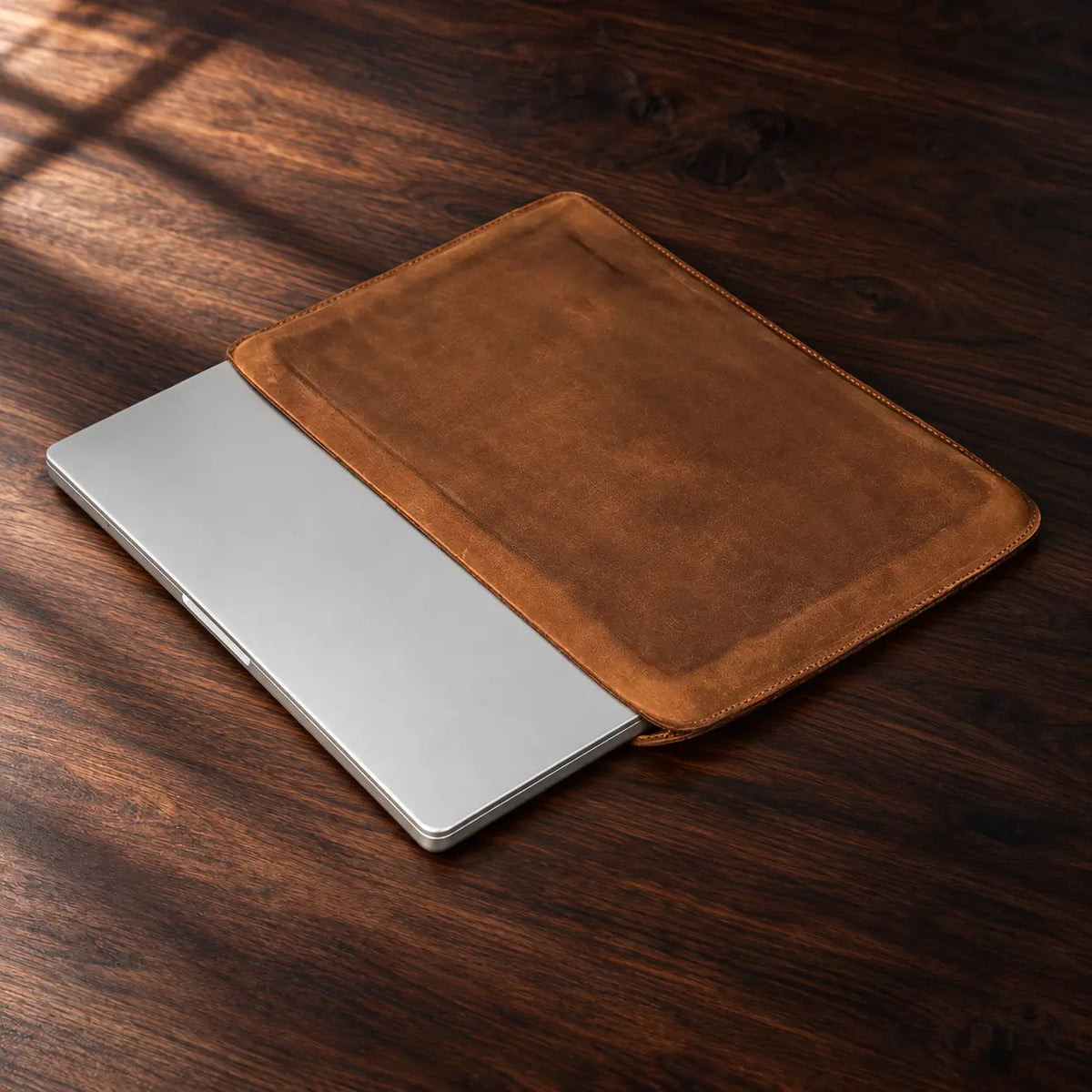 Pavia Cognac real-product view with closed laptop on dark walnut