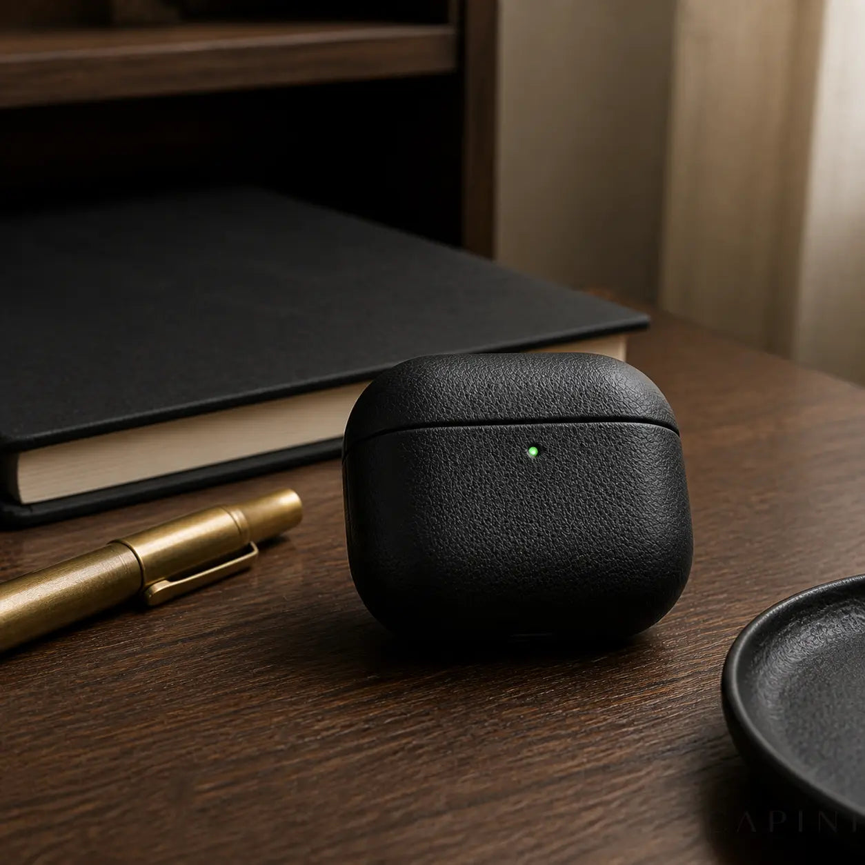Pesaro Fine Grain black AirPods 4 leather case on a walnut desk