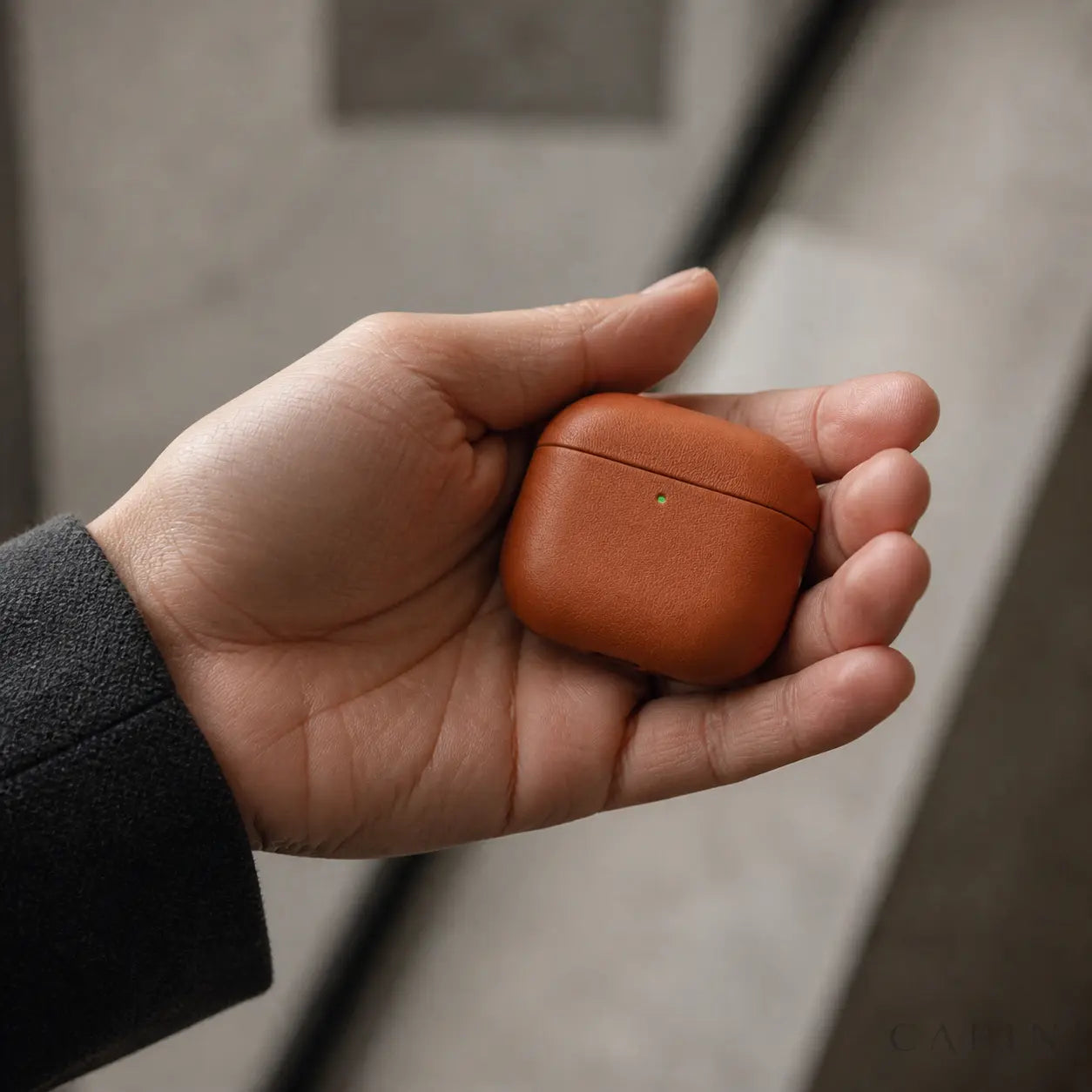 Pesaro Fine Grain cognac AirPods 4 leather case shown in hand