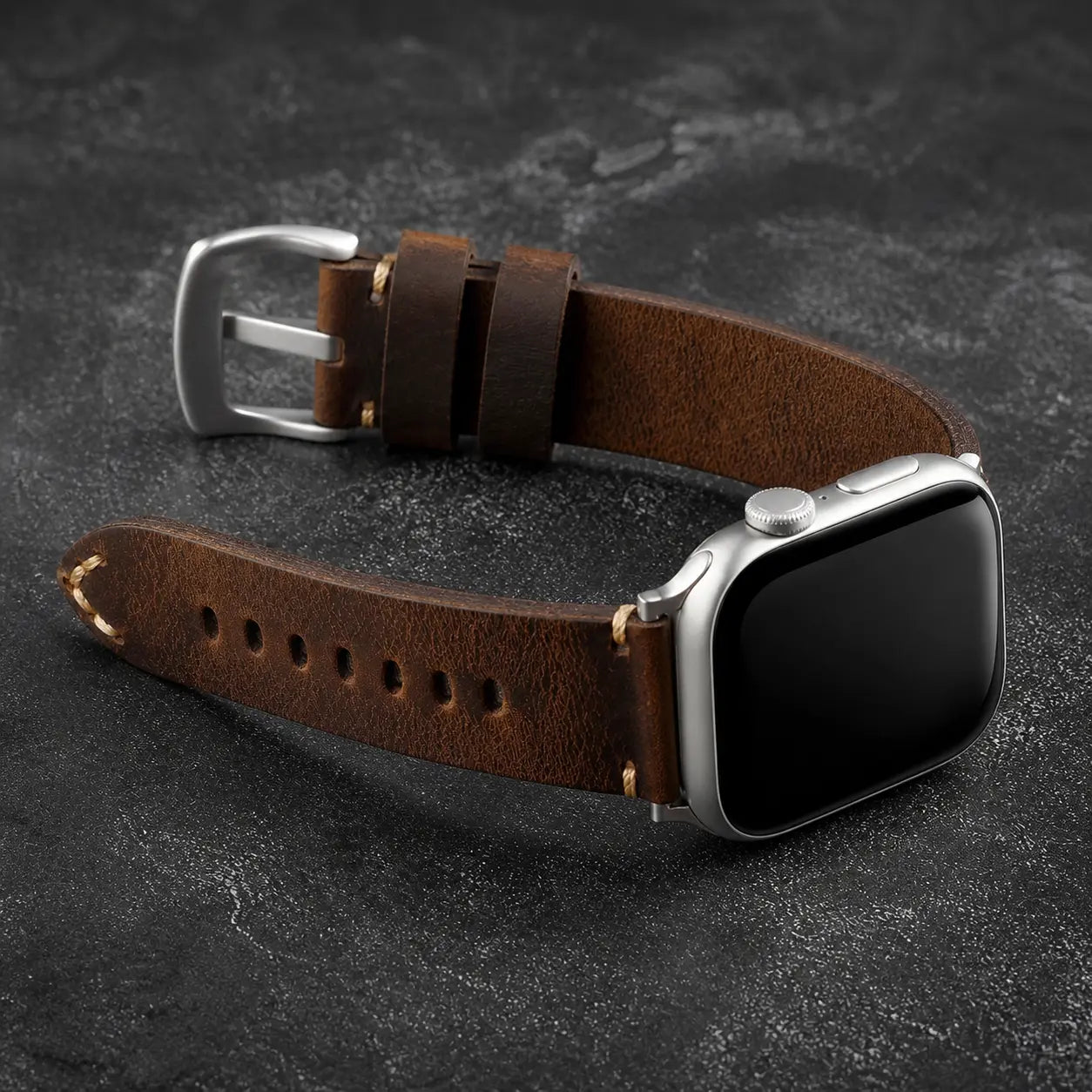 Antique brown Cremona Apple Watch strap with silver-tone hardware on dark stone
