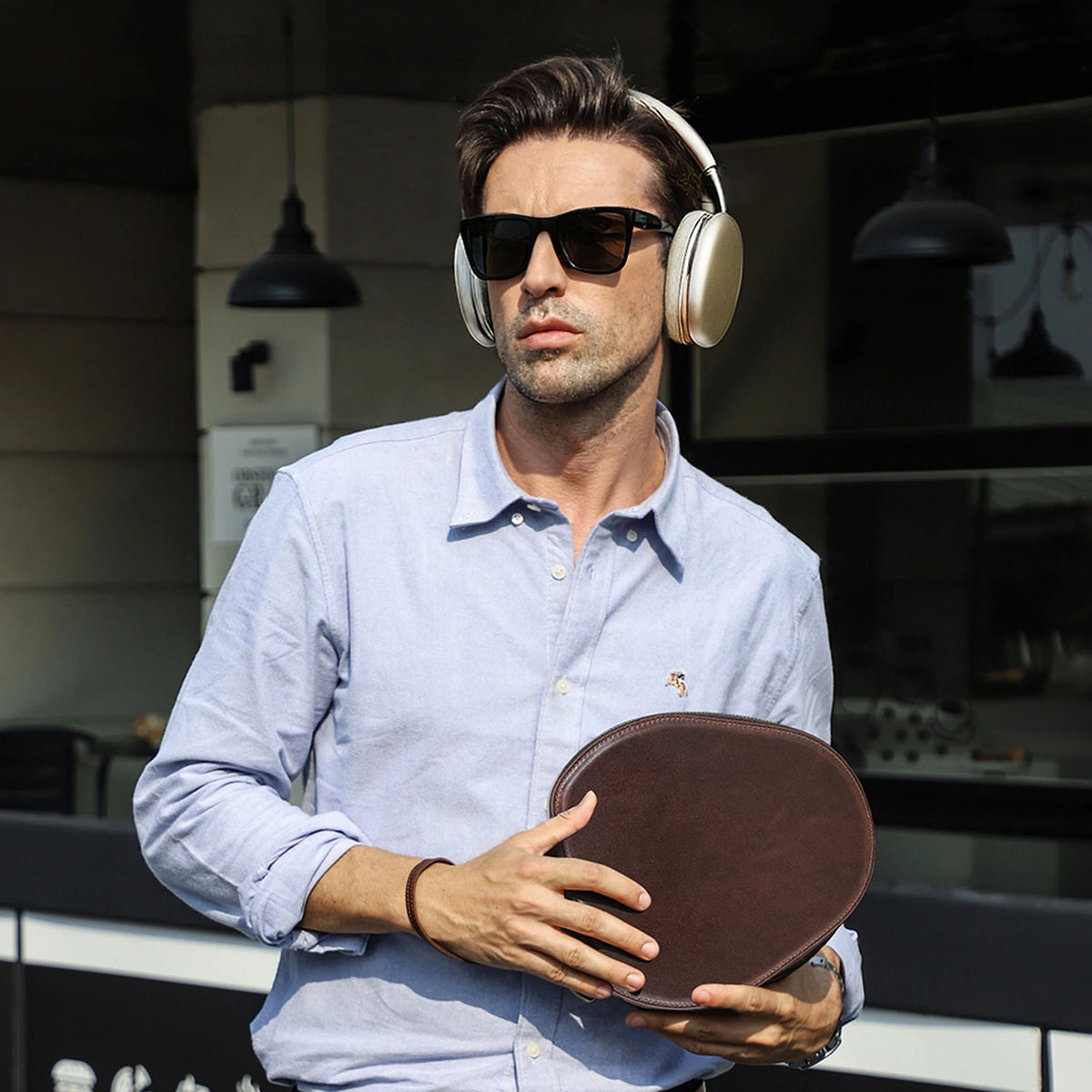 Man wearing AirPods Max, holding the Sanremo leather case