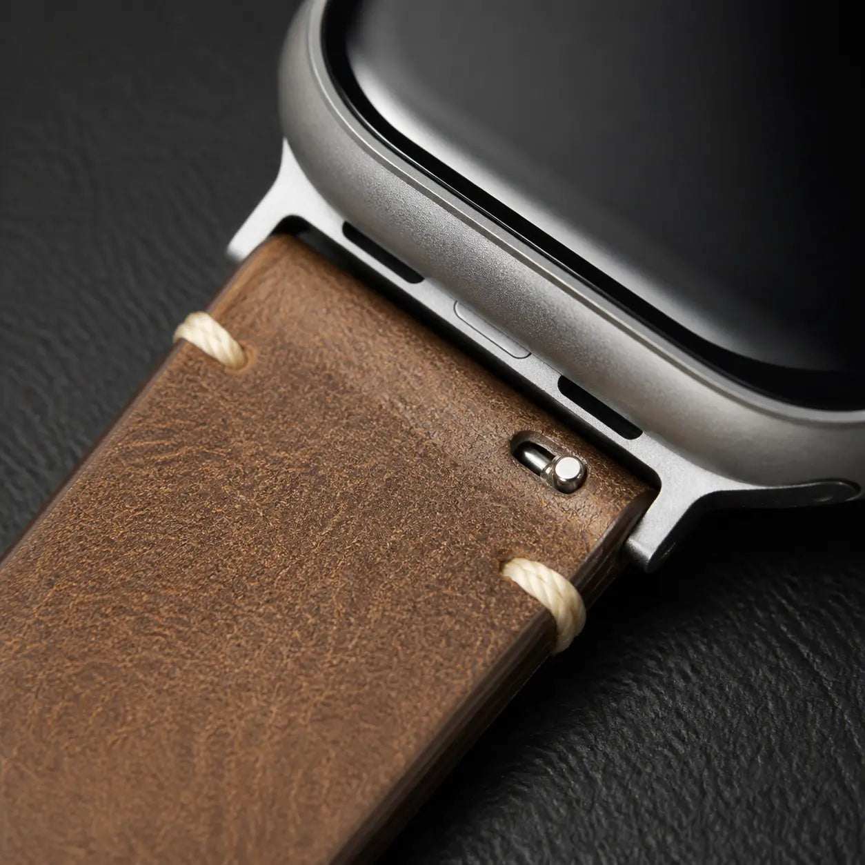 Close view of the Trieste oil-wax leather strap and stainless-steel Apple Watch adapter