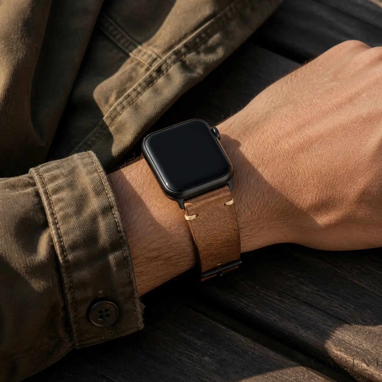 Brown Trieste oil-wax Apple Watch strap with black hardware worn outdoors