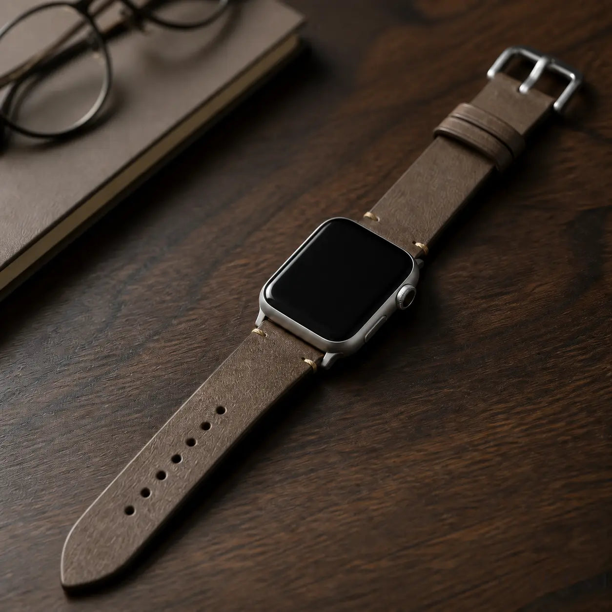 Coffee Trieste oil-wax Apple Watch strap with silver hardware on a walnut desk