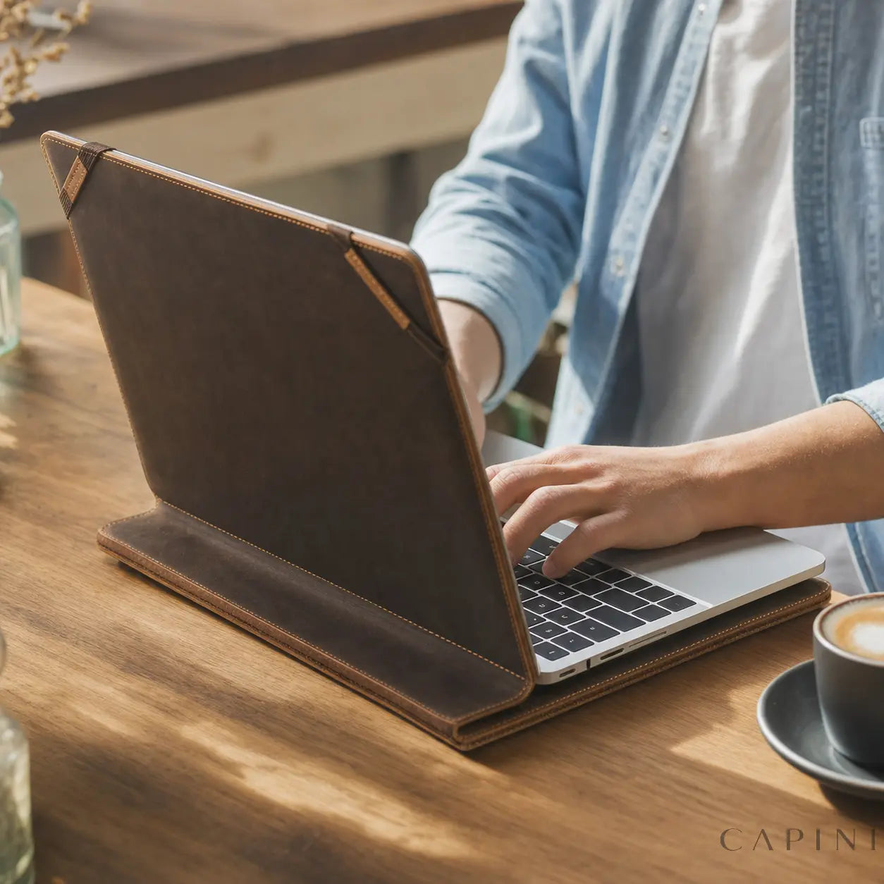 Fabriano Nubuck MacBook Folio open on a cafe table with a MacBook secured by leather corner retainers