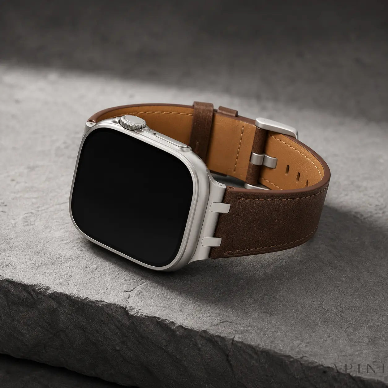 Dark brown Terni Two-Tone Apple Watch strap with titanium-tone hardware on grey stone
