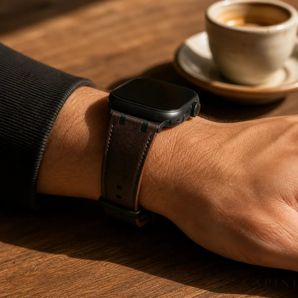 Dark brown Terni Two-Tone Apple Watch strap with matte black hardware worn at a cafe